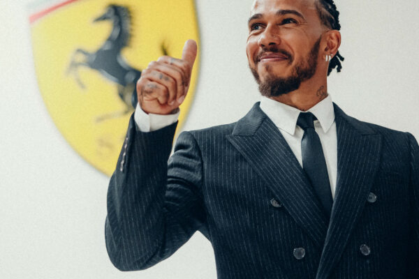 Lewis Hamilton standing in front of Ferrari logo